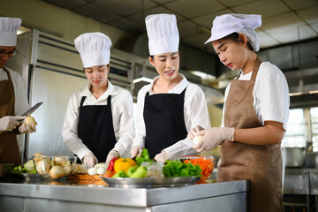 Cooking school instructor explaining food preparation techniques to students in a kitchen