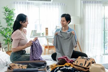 Obraz premium Asian young beautiful couple preparing clothes and packing suitcase. 