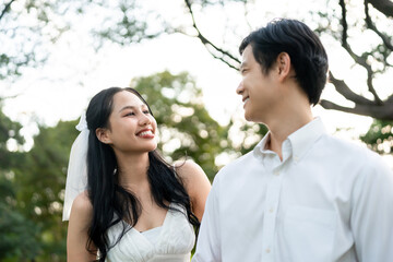 Obraz premium Asian romantic married couple looking each other in park during sunset. 