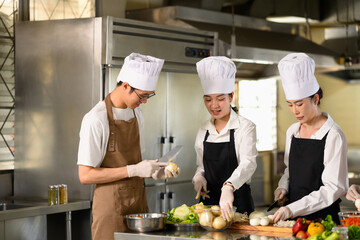 Group of cooking school students preparing fresh vegetables during a culinary class