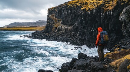Obraz premium A traveler with a backpack navigating a rocky coastline with waves crashing below.