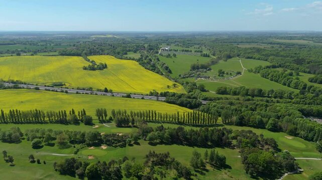 Aerial drone rural green agriculture landscape rapeseed England UK Spring summer Sunshine evening motorway roads countryside 