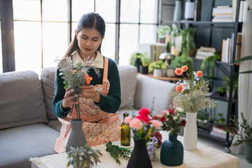 Happy asian Woman arranging flowers caring for home greenery