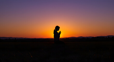 Obraz premium Silhouetted Woman Praying at Sunset