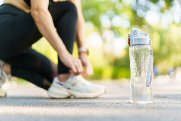 Woman tie a shoelace while running in the park.