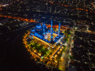 Aerial Night View of Sheikh Zayed Grand Mosque in Solo, Central Java, Indonesia Illuminated with Blue Lights Surrounded by Cityscape