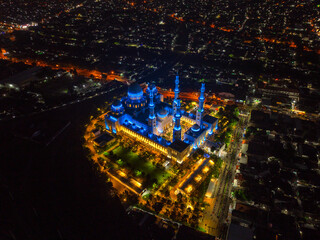 Aerial Night View of Sheikh Zayed Grand Mosque in Solo, Central Java, Indonesia Illuminated with Blue Lights Surrounded by Cityscape