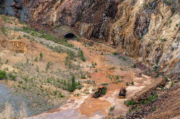 Explore the former copper mine in Falun, Sweden, where two rusted bulldozers lie abandoned amid the colorful mineral landscape, capturing the essence of a historical site
