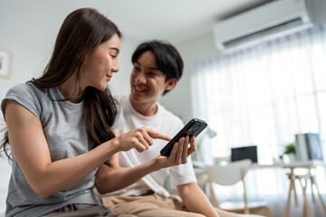 Asian young couple using smartphone shopping online in bedroom at home. 