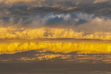 A layered cloud formation is brightly lit by the afternoon sun.