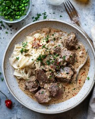 Beef Stroganoff with Noodles in Bowl Overhead Shot Delicious Meal Creamy Sauce Parsley Peas Fork Spoon