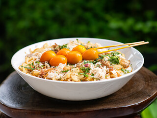 A bowl of Indonesian chicken porridge (bubur ayam) served with shredded chicken, fried shallots,...