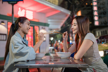 Asian beautiful women traveler eating street food outdoors in the city.