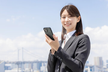 スマホを持ったスーツの若いビジネスウーマン
