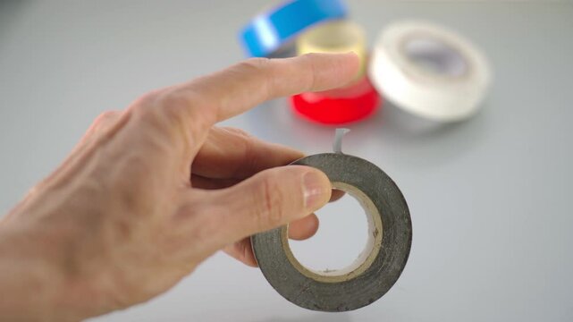 Hand testing adhesion strength of gray duct tape roll