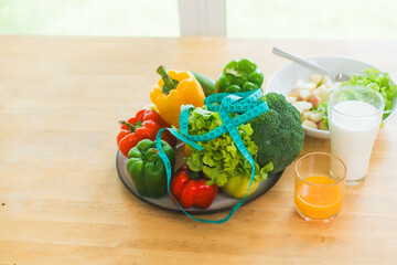 A fresh assortment of colorful vegetables, orange juice,milk highlights a balanced diet.The measuring tape symbolizes healthy eating,weight control,nutrition-focused lifestyle choices for wellness