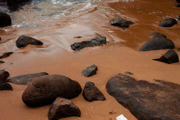 Close-up of foamy sea water splashing gently over smooth coastal rocks. A tactile glimpse into the dynamic interaction between land and ocean.
