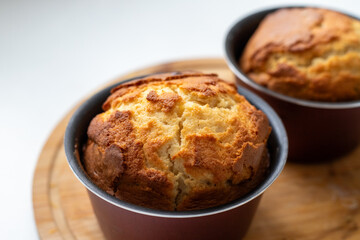Two muffins in a pan on a wooden cutting board. The muffins are golden brown and look freshly baked. Homemade baking and pastry from wheat flour. Making bread and Easter muffins