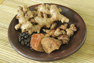 A plate of ingredients for traditional medicine. Ginger, kencur, Javanese sugar, kedawung seeds