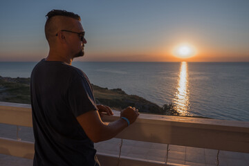 A man in sunglasses swims in a blue pool. Vacation at the hotel by the sea, sunset and mountains. Happy dad, family happiness. Muscles and a beautiful figure, black hair. High quality photo