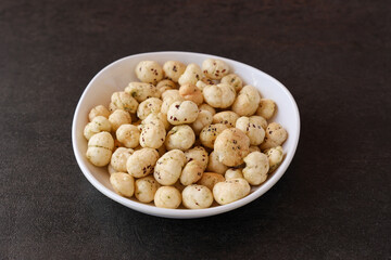 Bowl with puffed Lotus seed. Indian Organic Makhane Makhana puffed lotus seed or Fox nuts. Flavoured Prickly Water Lily. Edible seeds popular in India