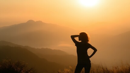 Fototapeta premium Silhouetted figure gazing at sunrise over misty mountains.