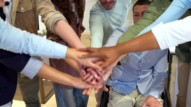 Startup team celebrating success with stacked hands and raised arms