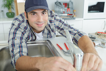 young repairman fixing the kitchen tap