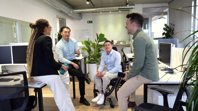 Business people chatting in modern office with disabled colleague