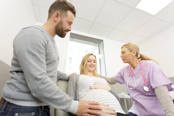 Obraz premium pregnant woman with her husband visiting the doctor in clinic