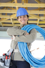 enthusiastic female builder holding a reel of blue pipe