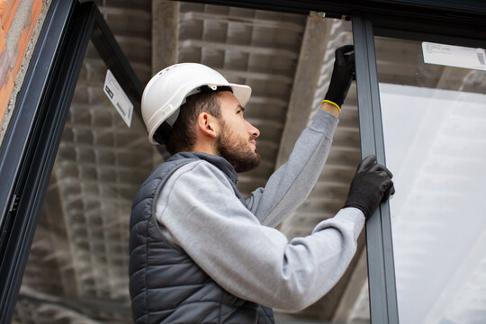 construction worker installing window in house