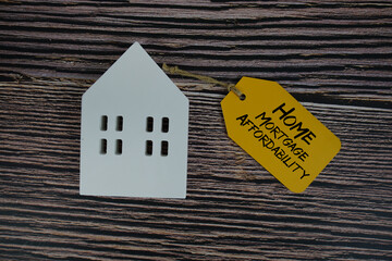 Home Mortgage Affordability text on price tag with white house model flat lay on wooden background