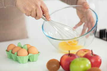 female chef beating eggs with wire whisk in bowl