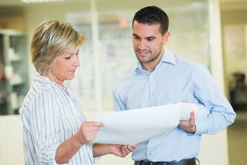 Obraz premium mature woman showing papers to male colleague in office