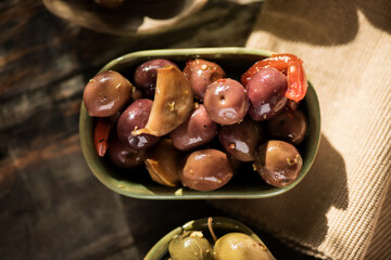 Olives, homemade marinated colorful olives with herbs and spices on rustic table, close up. Healthy Mediterranean vegan food. Top view, flat lay  