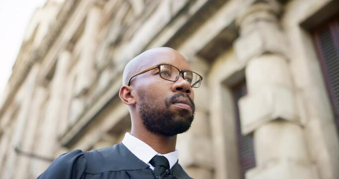Walking, judge and man in city with books for law, journey and arrival at magistrate court building in low angle. African person, lawyer and travel outdoor for legal, judicial and commute for justice