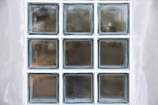 Close up transparent clear glass block on concrete wall under construction. To apply sealant at groove edge around border glass block. Construction material for light go inside room.