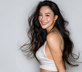 A young woman with a bright smile and beautiful, flowing black hair is suitable for advertising shampoo, conditioner, cosmetic products, fashion and beauty. 