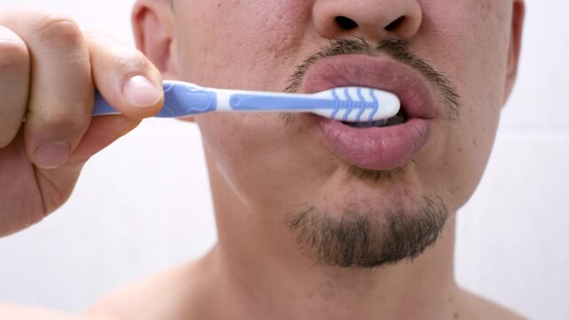 The man brushes his teeth with toothbrush with toothpaste close-up.