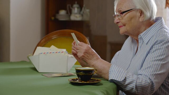 Relaxed Elegant elderly lady muses over sentimental personal letters