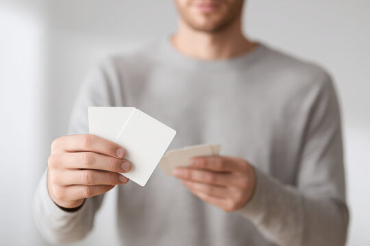 person holding playing cards in their hands against light background with soft lighting focusing on cards