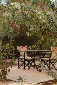 Blurred ambiente setup of chairs and a table in the garden of a luxury desert hotel in the Moroccan Sahara.