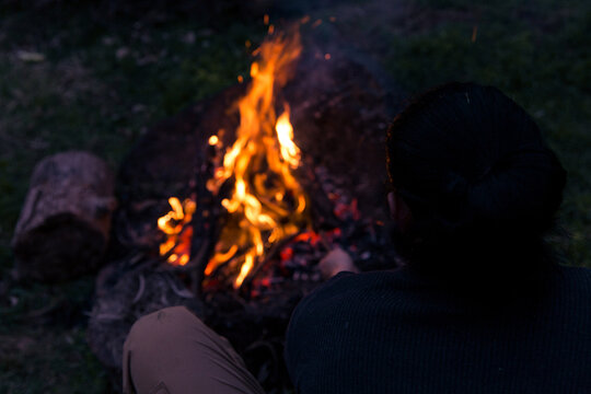 Man stoking roaring camp fire at night