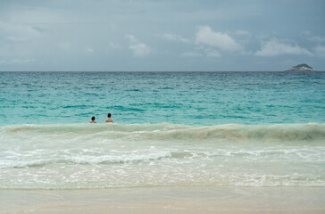 Tropical turquoise wave rolling to sandy beach in Seychelles, with foamy surf, calm horizon