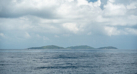 View of distant islands between Praslin and La Digue, Seychelles, with a sailboat on the ocean