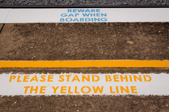 Warning sign to "Beware gap" and 'Stand behind the yellow line' at Harden railway station
