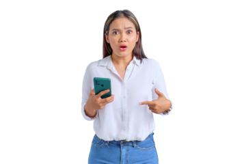 Shocked young Asian woman pointing fingers at mobile phone and looking at camera isolated on transparent background