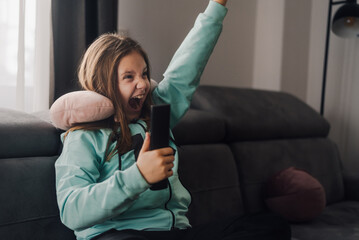 Excited girl cheering and watching tv at home