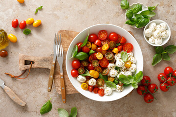 Salad with fresh cherry tomatoes, mozzarella and basil leaves, top view